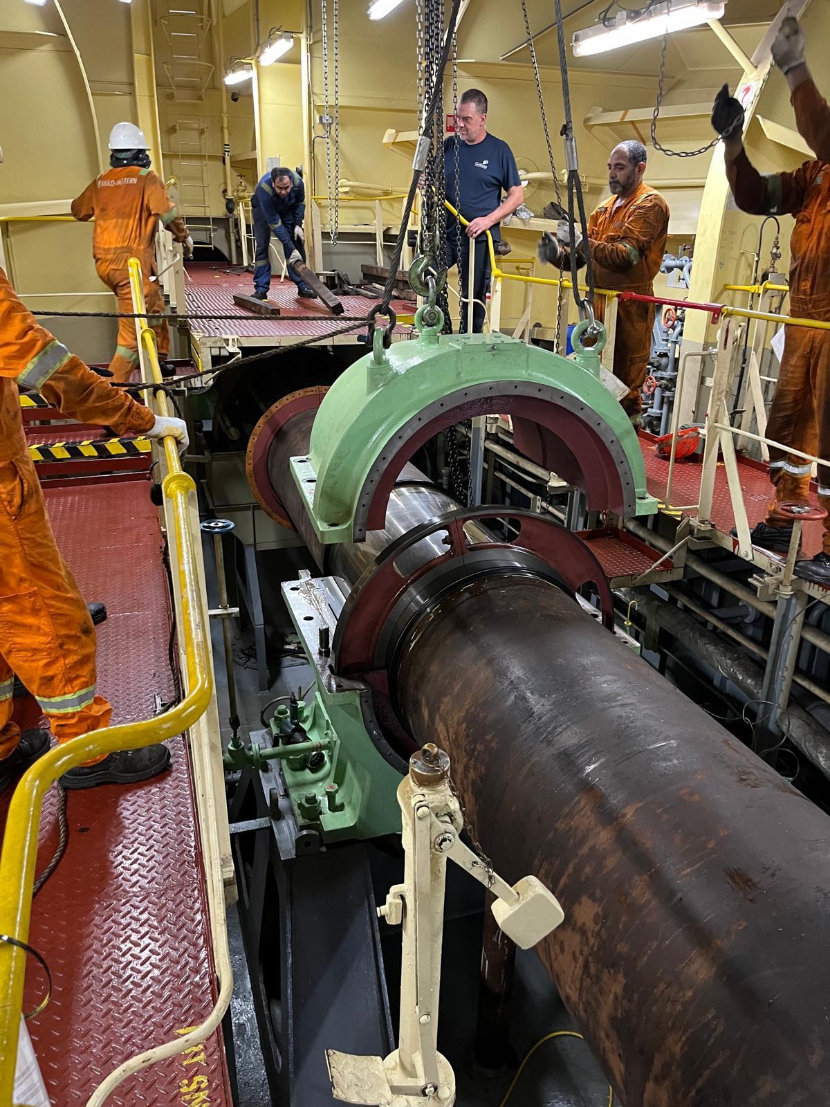 Crew installing a shaft bearing housing with chain hoist